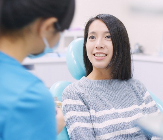 Woman in gray sweater smiling at her dentist