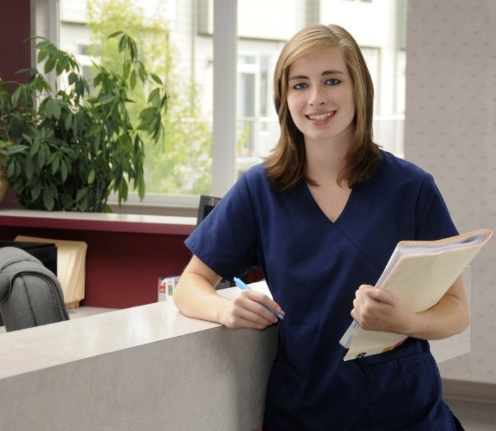 Smiling dental team member standing by front desk of Jersey City dental office