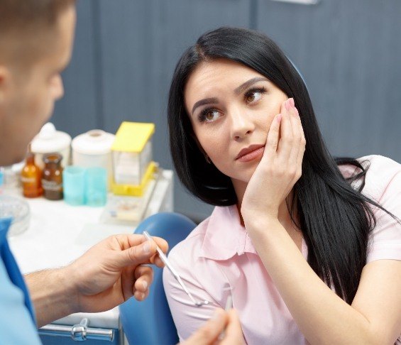 Emergency dental patient holding her cheek in pain