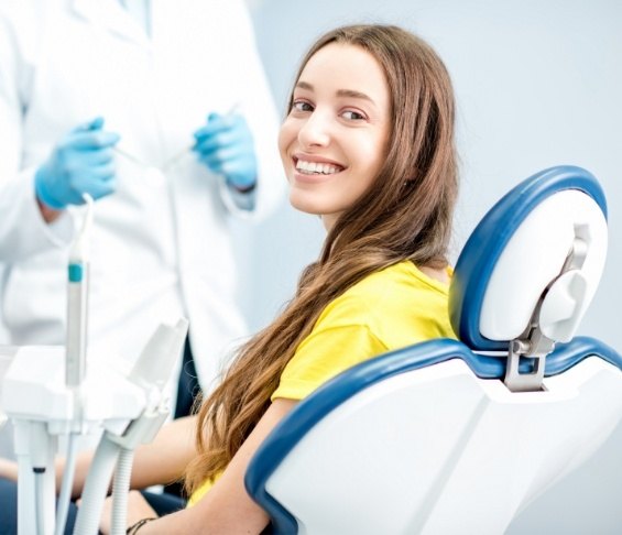 Woman in yellow shirt smiling in dental chair