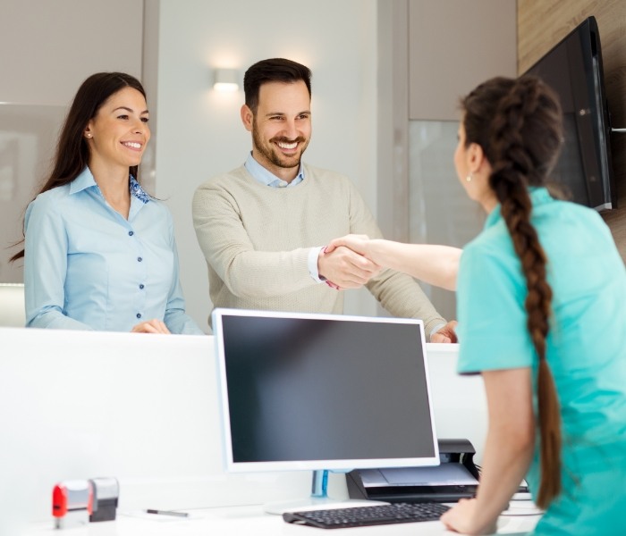 Man shaking hands with dental team member at front desk