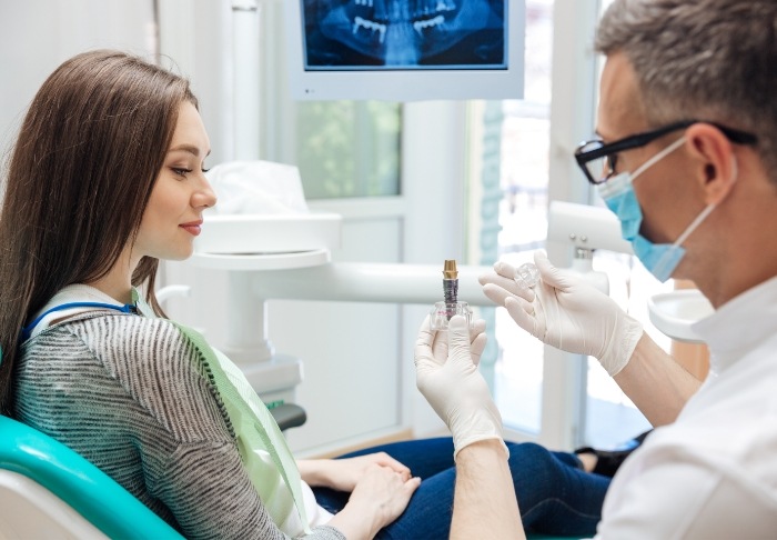 Dentist showing a model of a dental implant to a patient