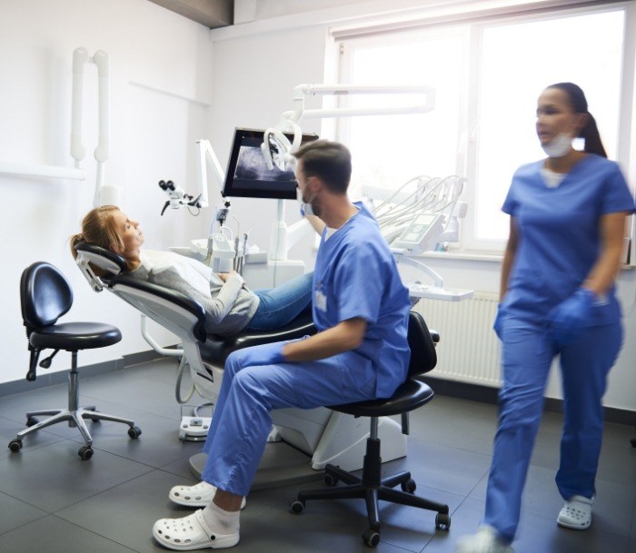 Two Jersey City dental team members talking to a patient in the dental chair