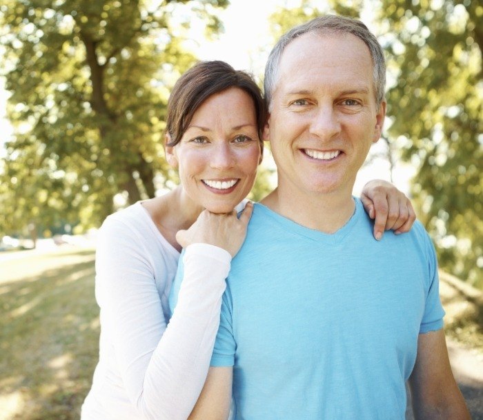 Smiling man and woman holding each other in a park