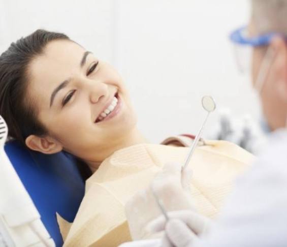 Woman in dental chair grinning at her dentist