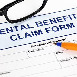 Dental benefits claim form with glasses and a pen